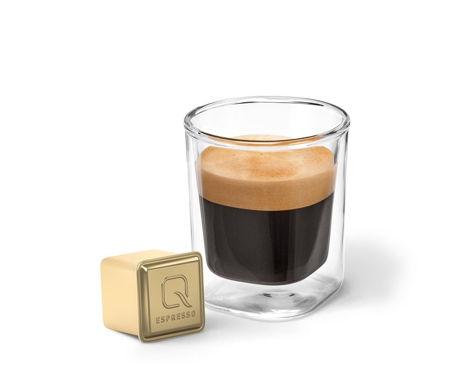 Ein Glas Espresso und eine goldene Kapsel Qbo Flavoured Espresso Raspberry White Choc.