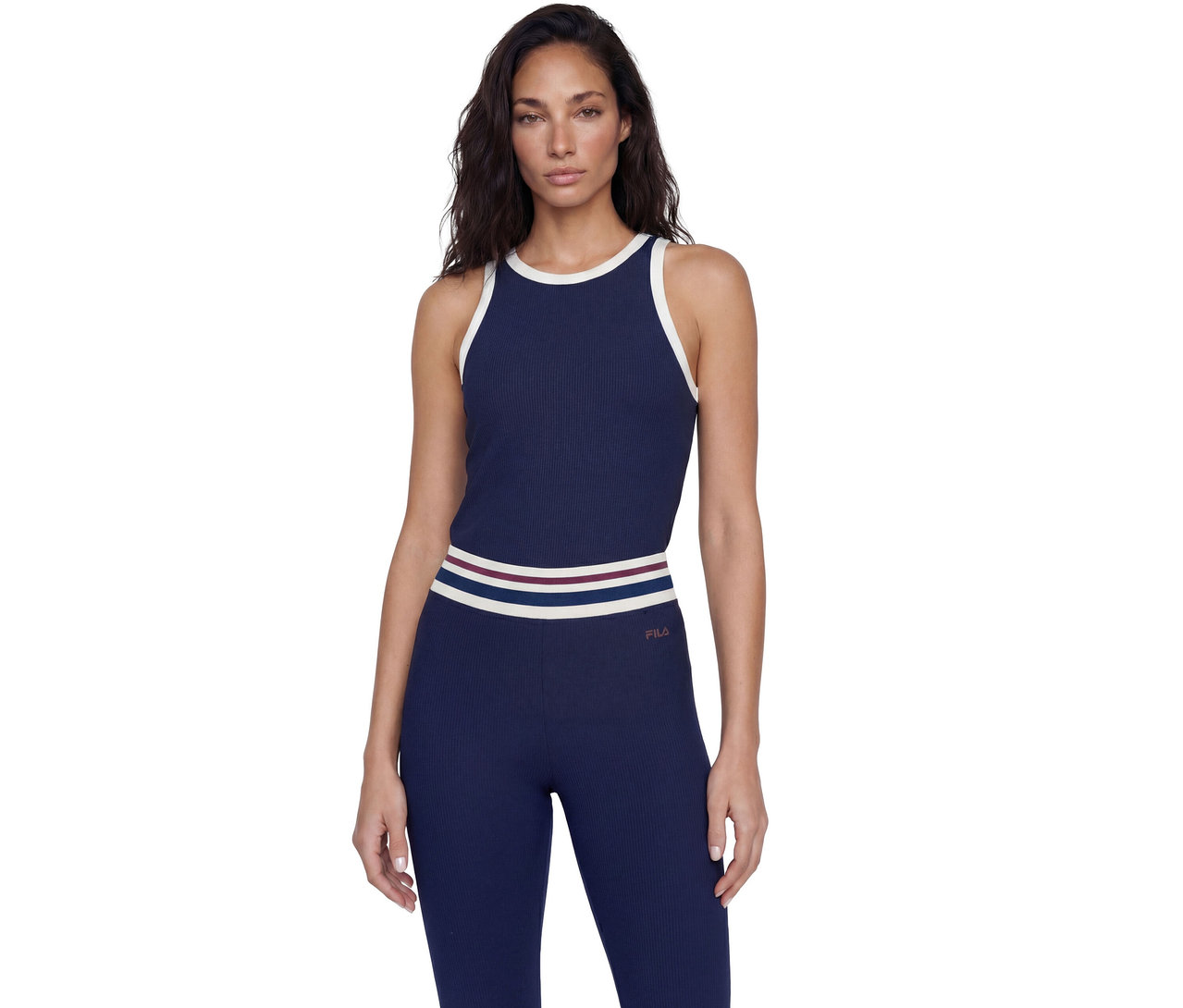 Frau in einem gerippten, marineblauen Tanktop mit weißem Besatz und passenden Leggings mit gestreiftem Bund, auf deren Hüfte das Fila-Logo zu sehen ist.