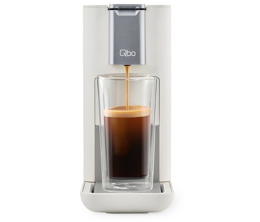 Kaffee wird aus einer Qbo ESSENTIAL Bright Sand Kaffeemaschine in ein Glas gegossen.
