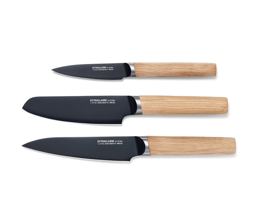 Drei Küchenmesser mit Holzgriffen liegen auf einem weißen Hintergrund.