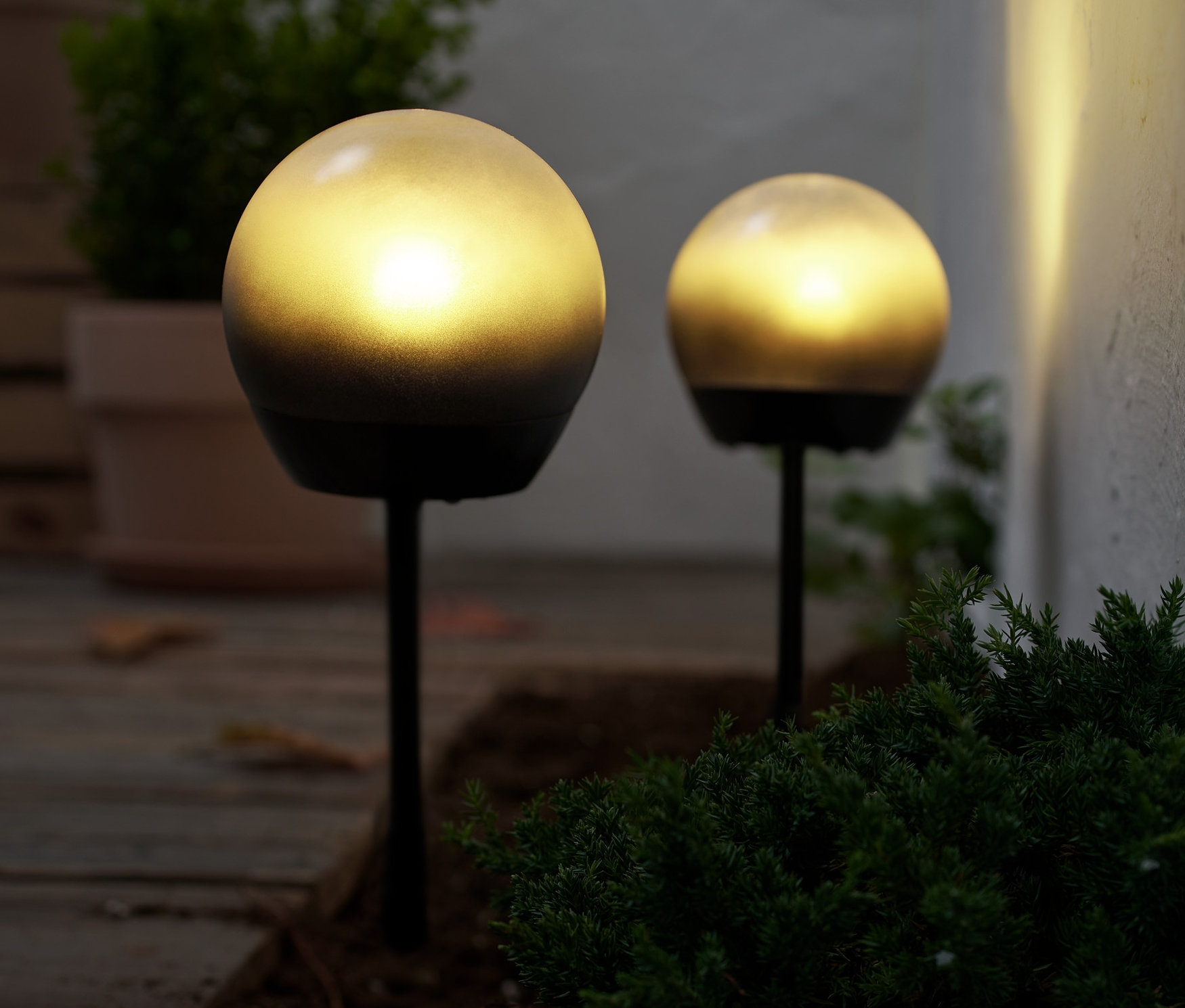 Zwei LED-Kugelleuchten beleuchten den Boden im Freien.