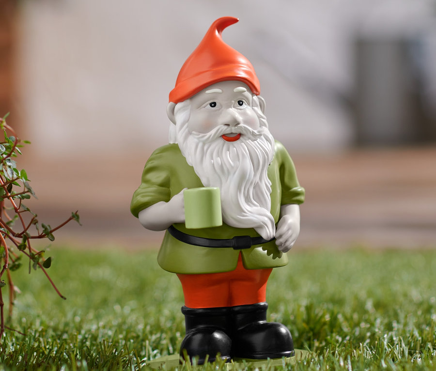 Ein Gartenzwerg steht auf dem Rasen und hält eine Tasse.