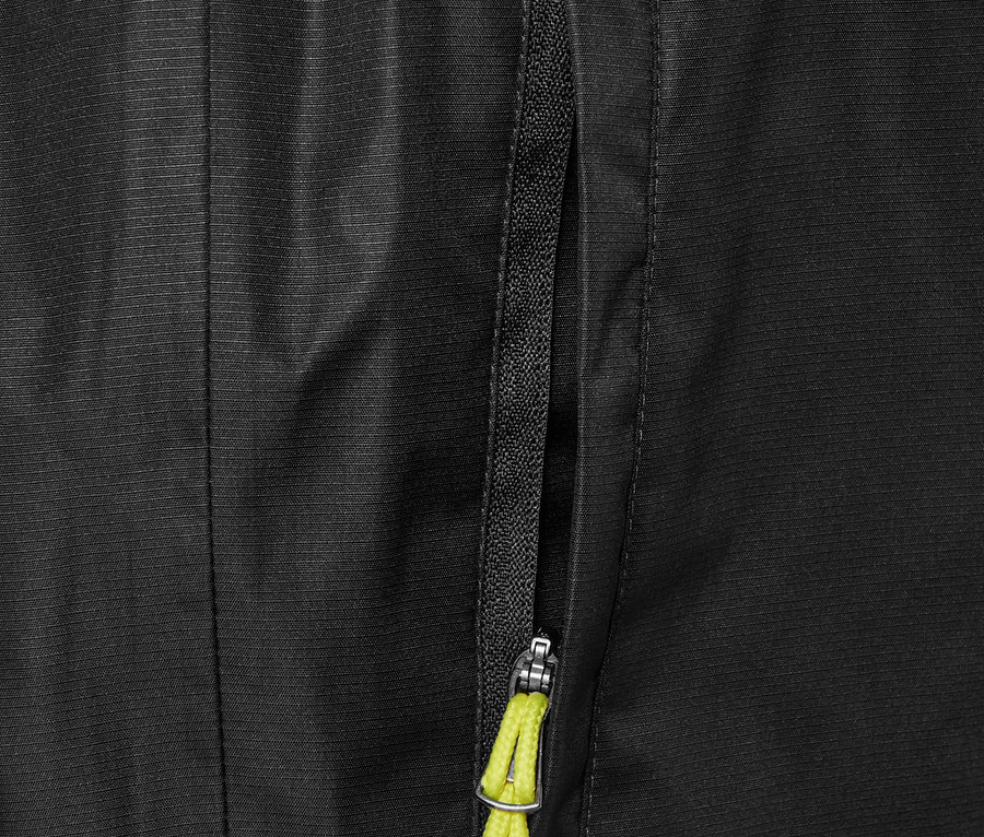 Detailaufnahme einer schwarzen Regenhose mit Reißverschlusstasche und gelbem Kordelzug.