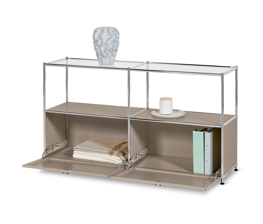 Ein Sideboard Metall »CN3« mit 2 Klappen und Glasböden in Taupe. Auf der oberen Ablage steht eine Vase, auf der unteren Decken und Bücher.