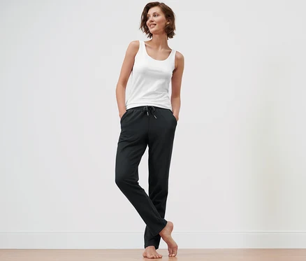Frau steht mit Händen in den Taschen der schwarzen Loungewear-Hose.