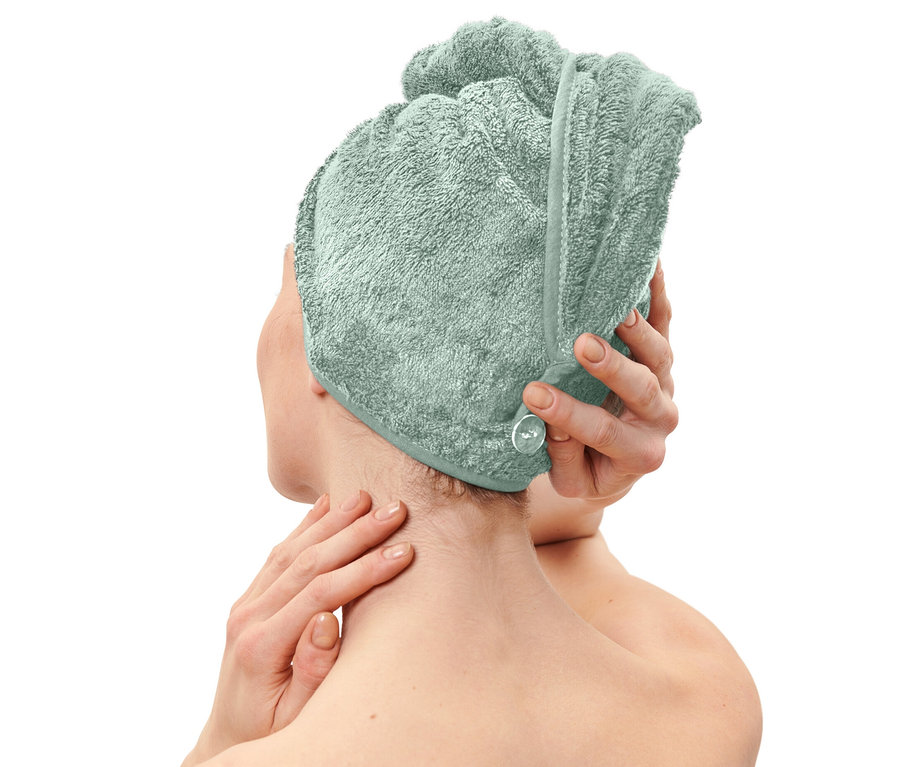 Frau setzt Turban-Handtuch in Hellblau auf.