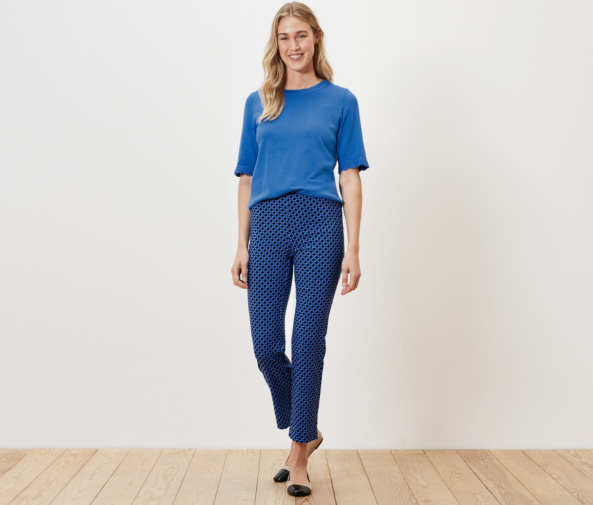 Frau posiert in kobaltblauen, bedruckten Stretchhosen und blauem Oberteil.