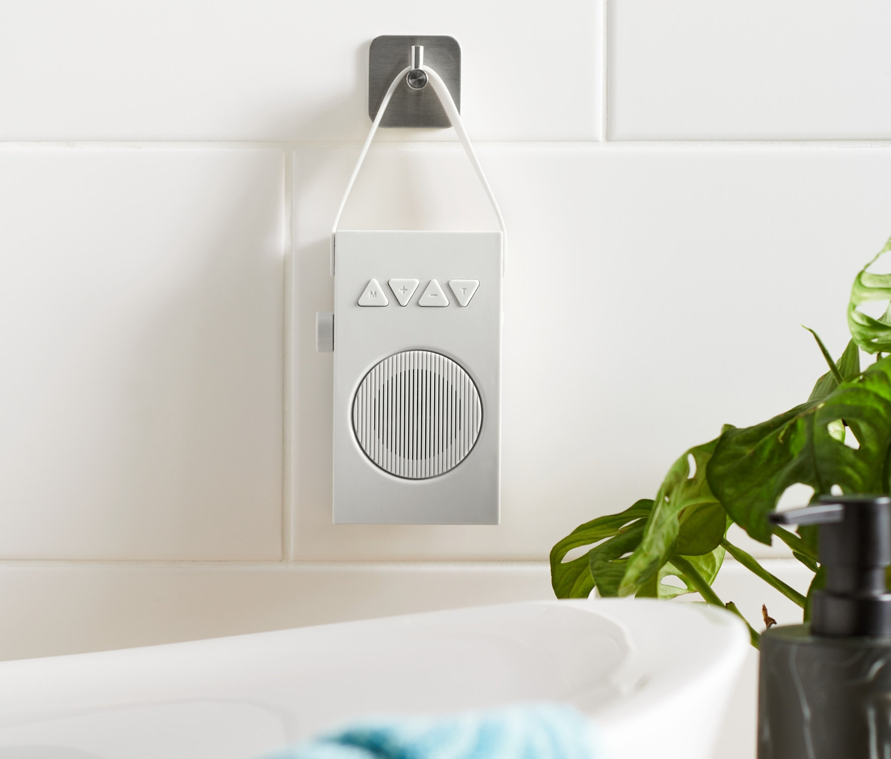 Ein weisses Badradio hängt an einer gefliesten Wand neben einer Badewanne.