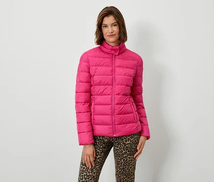 Frau posiert in rosa Steppjacke und Hose mit Tiermuster.