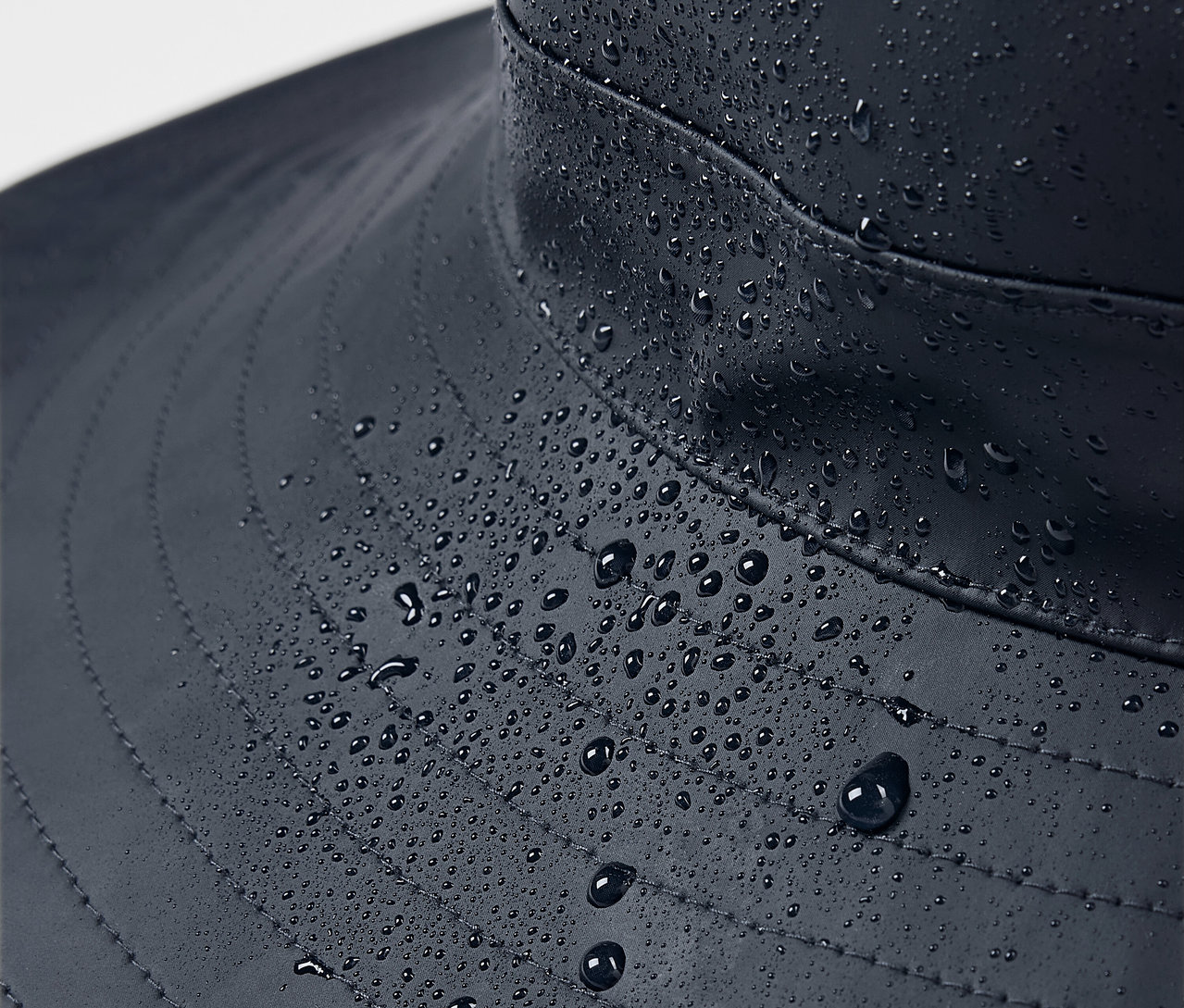 Nahaufnahme eines blauen Regenhuts mit Wassertropfen.