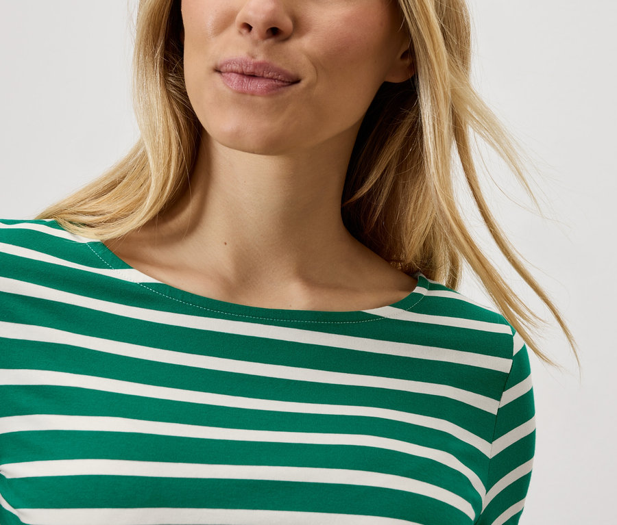 Blonde Frau trägt ein gestreiftes Shirt.