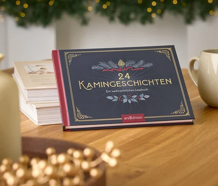 Buch "24 Kamingeschichten" auf einem Holztisch neben einer Tasse und einer Vase, im Hintergrund ein Weihnachtsbaum.