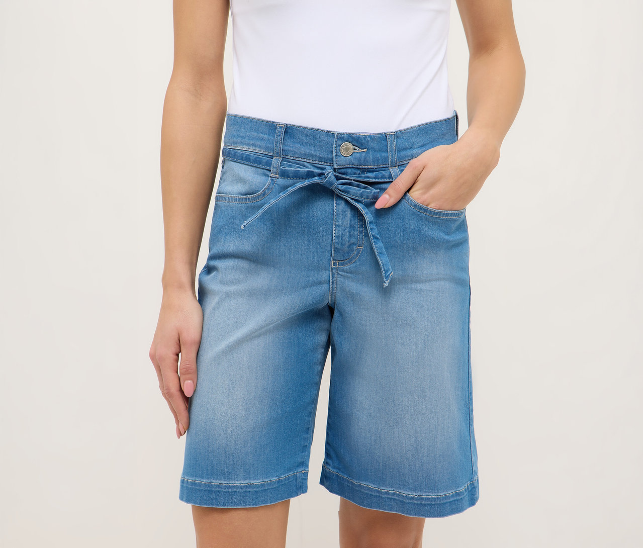 Frau mit hellblauen Angels Denim »Lia City« Shorts mit Bindegürtel und weißem Top.