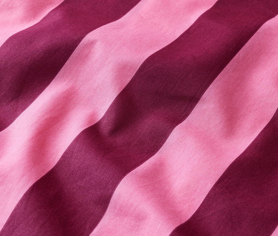 Nahaufnahme von rosa- und burgunderfarben gestreiften Stoffbahnen, die diagonal verlaufen.