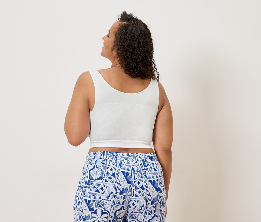 Frau von hinten in weißem Crop-Top und blau-weiß gemusterter Hose.