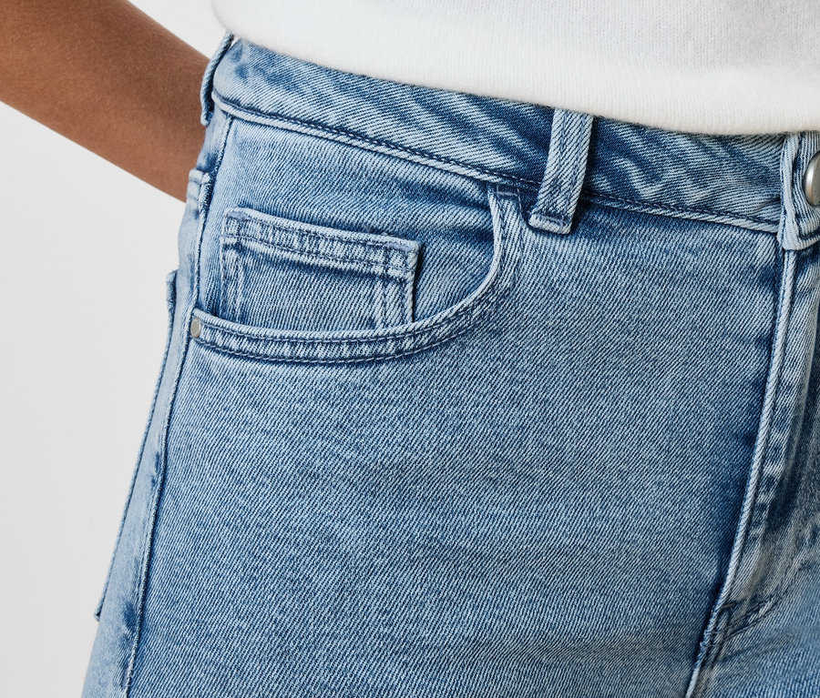 Nahaufnahme einer hellblauen Jeanshose mit Taschen und Knopf.