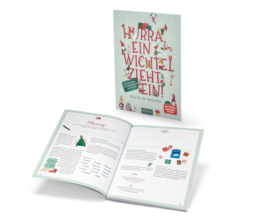 Das Buch »Hurra, ein Wichtel zieht ein!« ist geöffnet und steht dahinter.