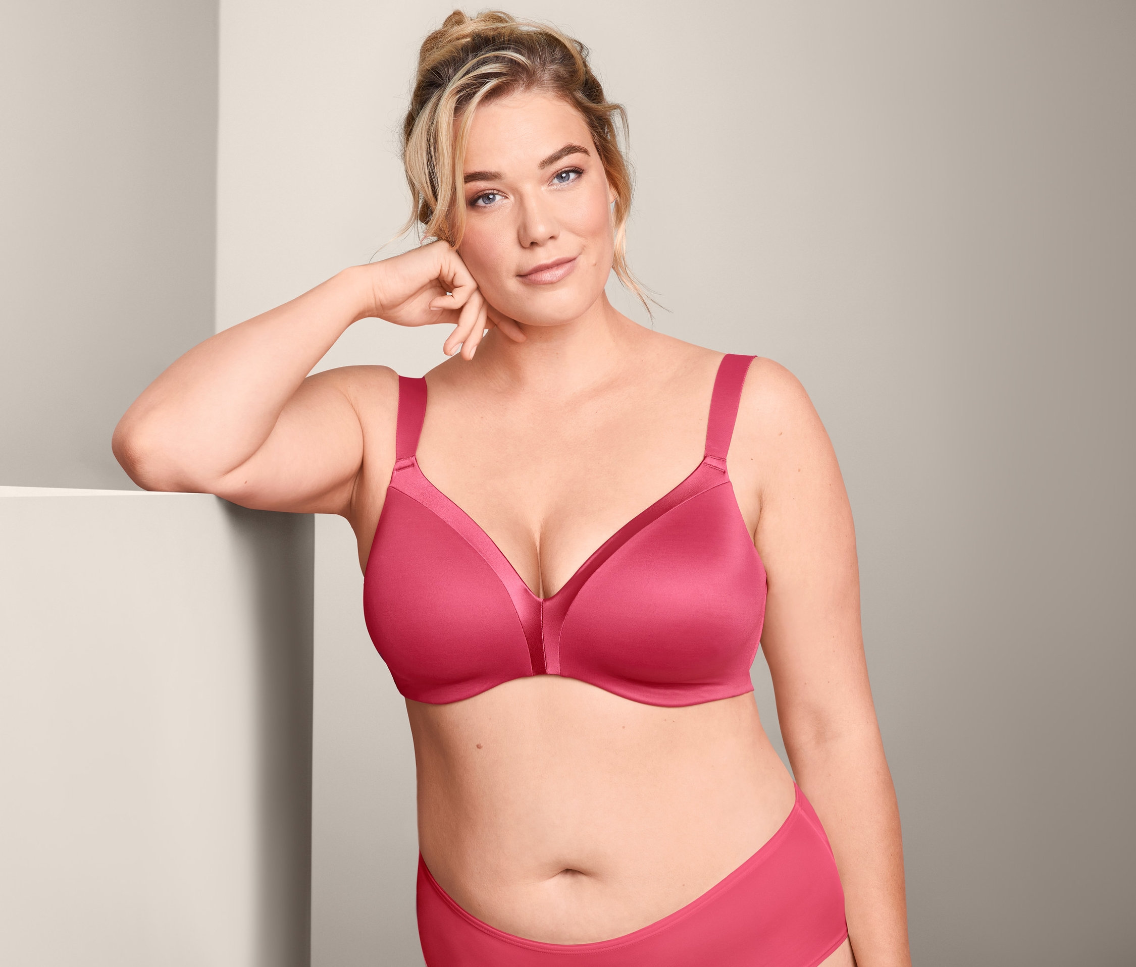Frau, die sich an ein weißes Objekt lehnt, trägt einen rosafarbenen Softschalen-BH.