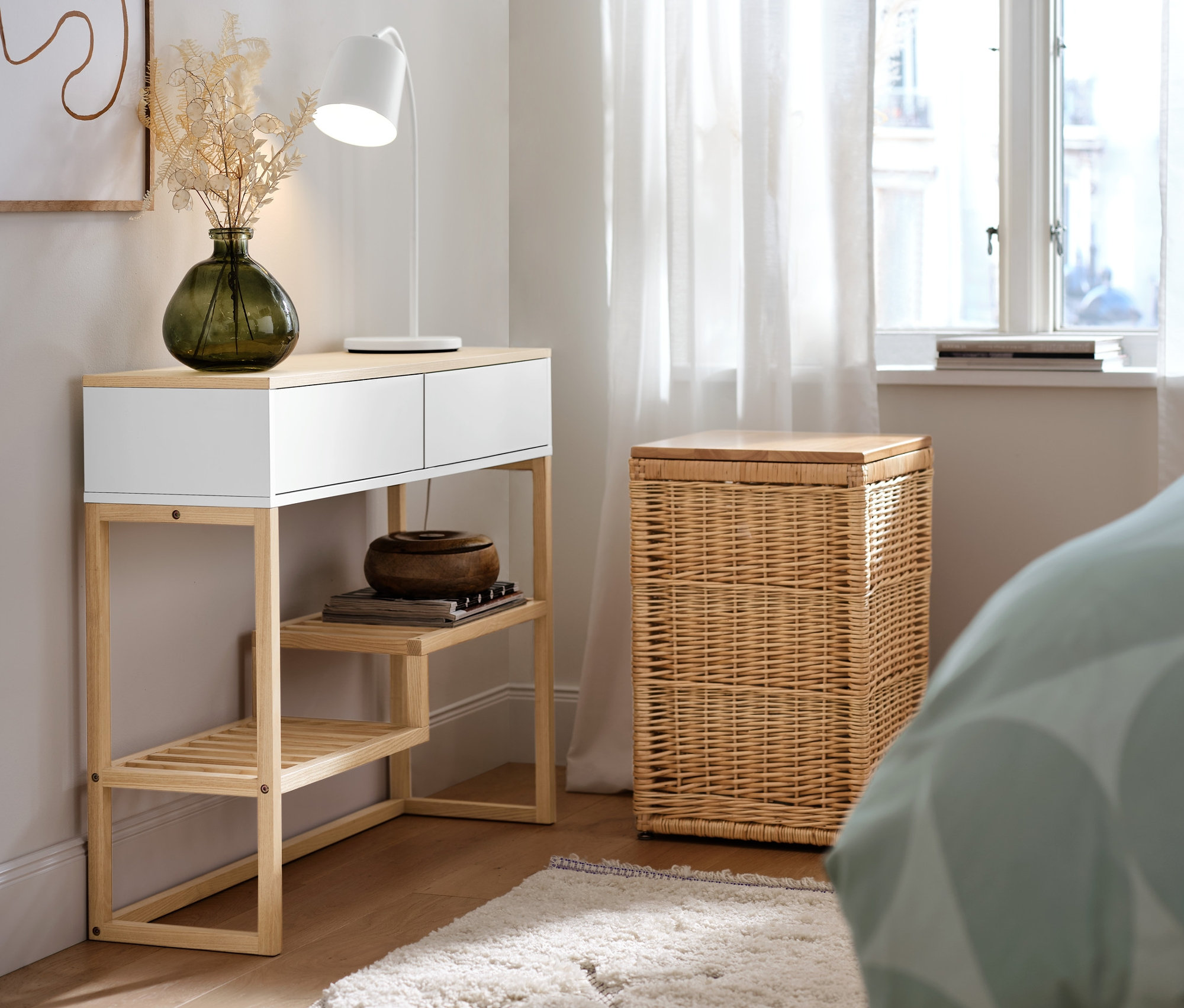 Eine hohe Truhe aus Geflecht steht neben einer Konsole mit Schubladen. Auf dem Boden liegt ein Indoorteppich »NATIVO Boho Lines«.