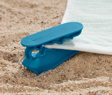 Blauer 4 Handtuchclip befestigt ein Handtuch im Sand.