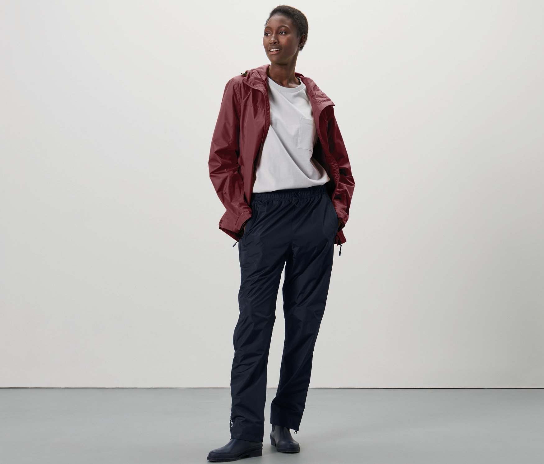 Frau steht und trägt eine Unisex-High-Tech-Regenhose.