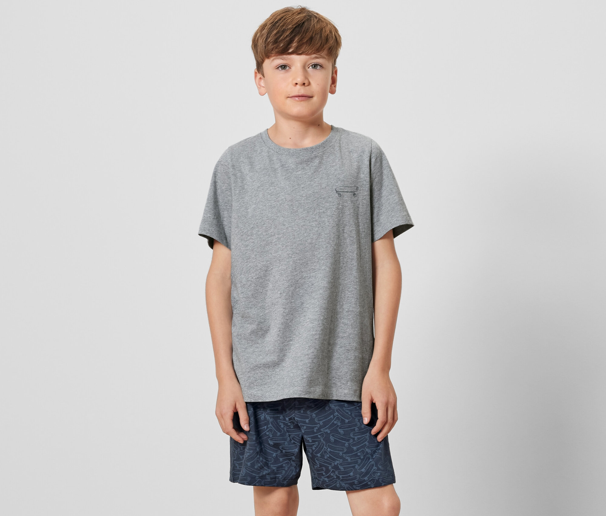 Junge in grauem T-Shirt und Kinder-Shorty-Pyjama.