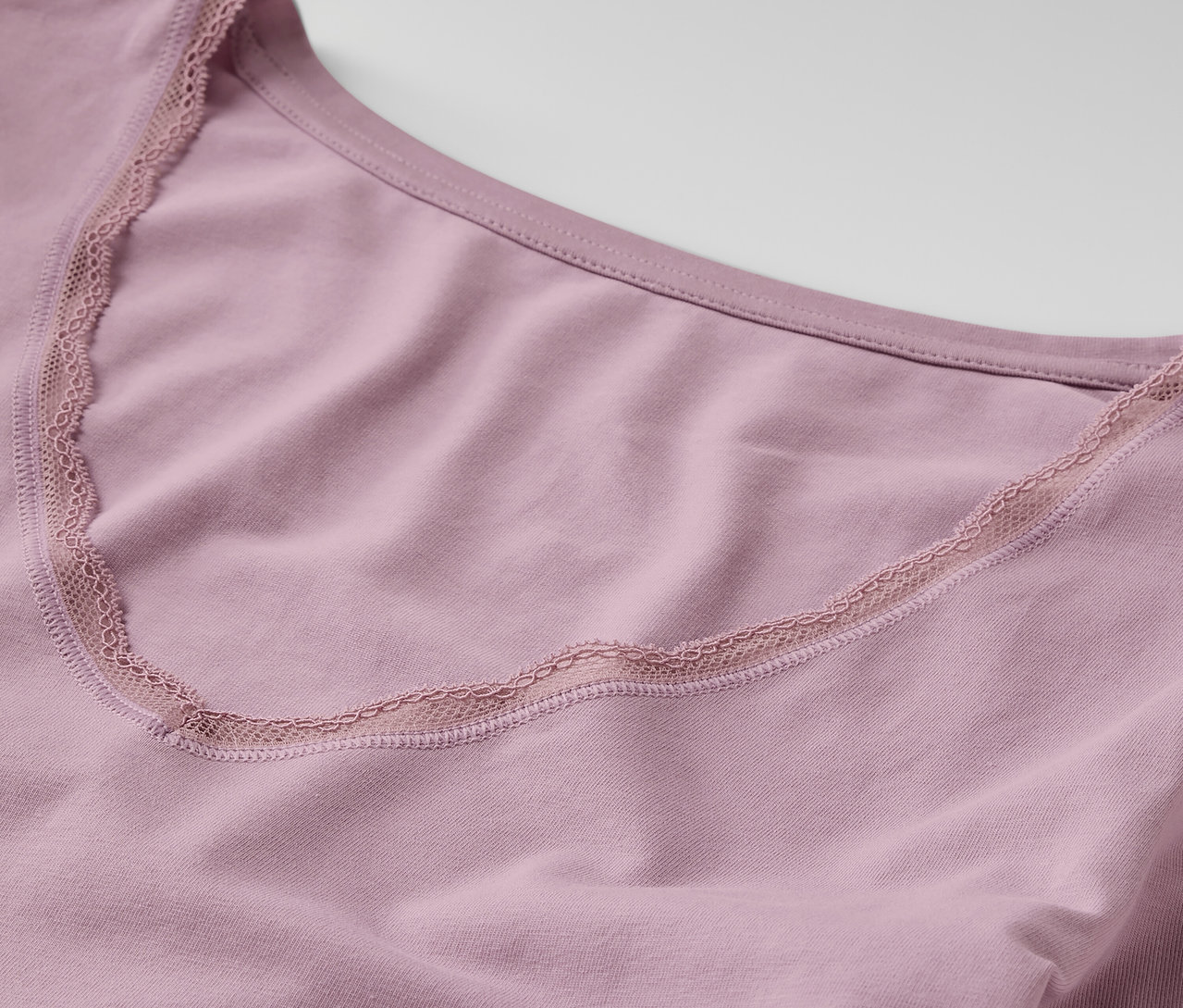 Detailansicht eines lila Langarm-Unterhemds mit Spitzensaum.
