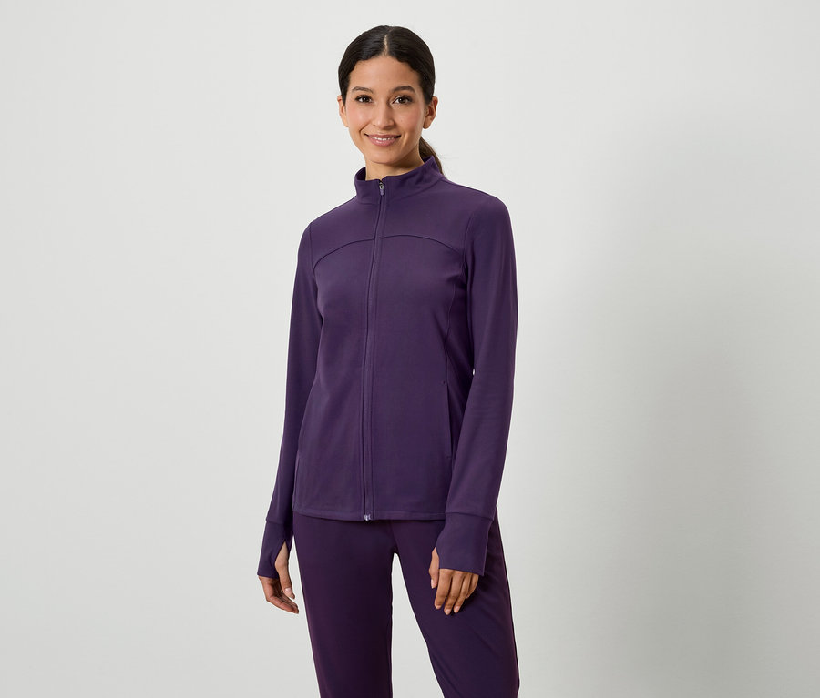 Frau posiert in einem lila Jacken- und Hosenanzug.