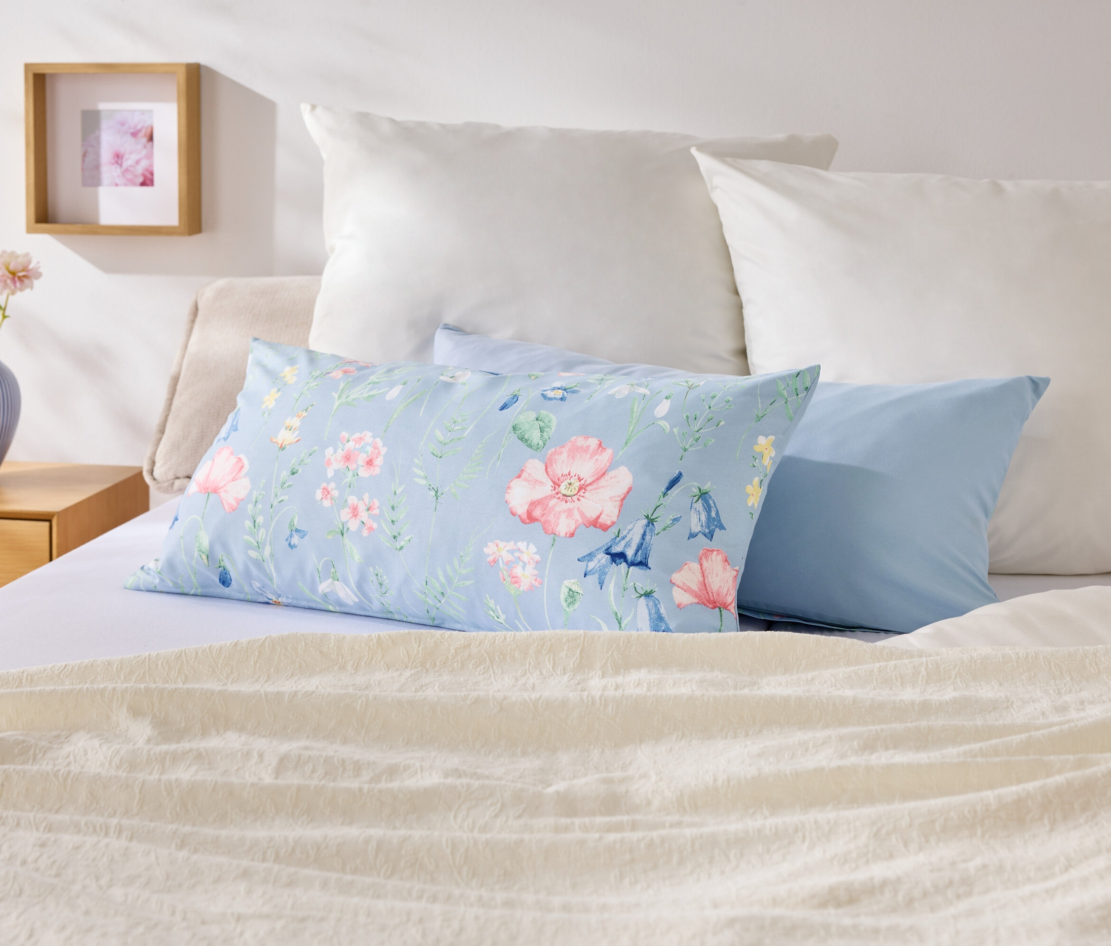 Auf einem Bett liegen Kissen in verschiedenen Farben und Mustern.