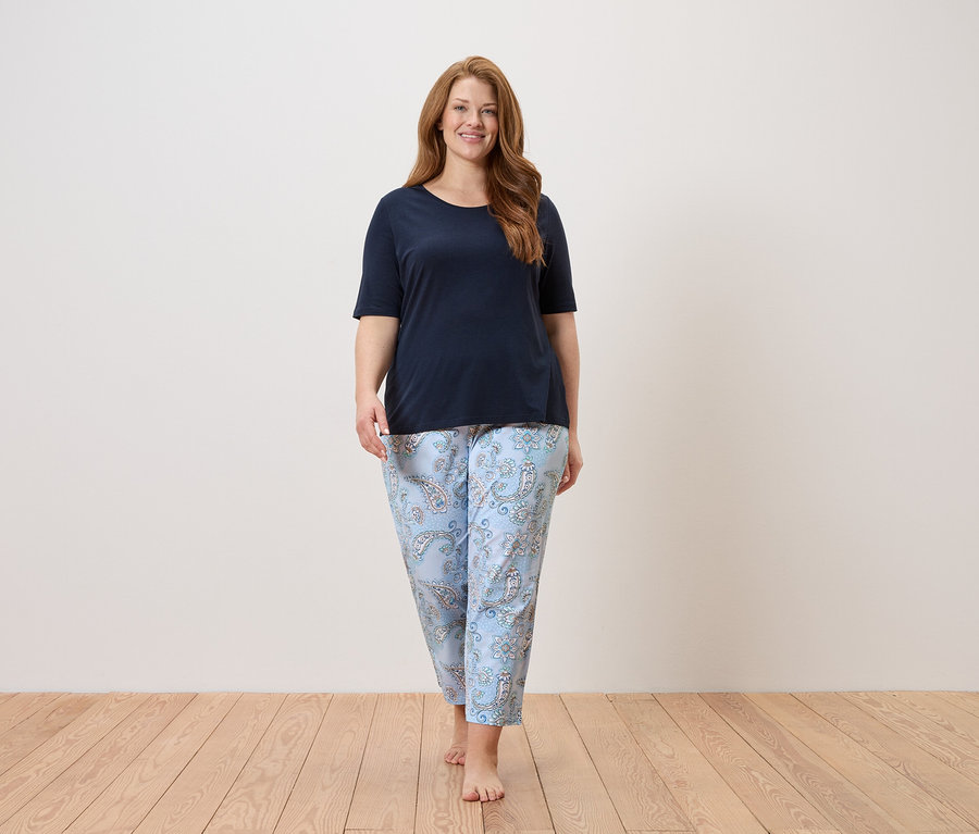 Frau geht barfuß in marineblauem Oberteil und hellblauer Hose mit Paisleymuster.