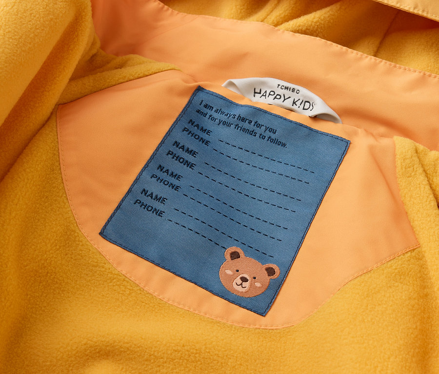 Gelbe Jacke mit gelbem Fleecefutter. Aufnäher mit "Name" und "Telefon" und Teddybär-Motiv.
