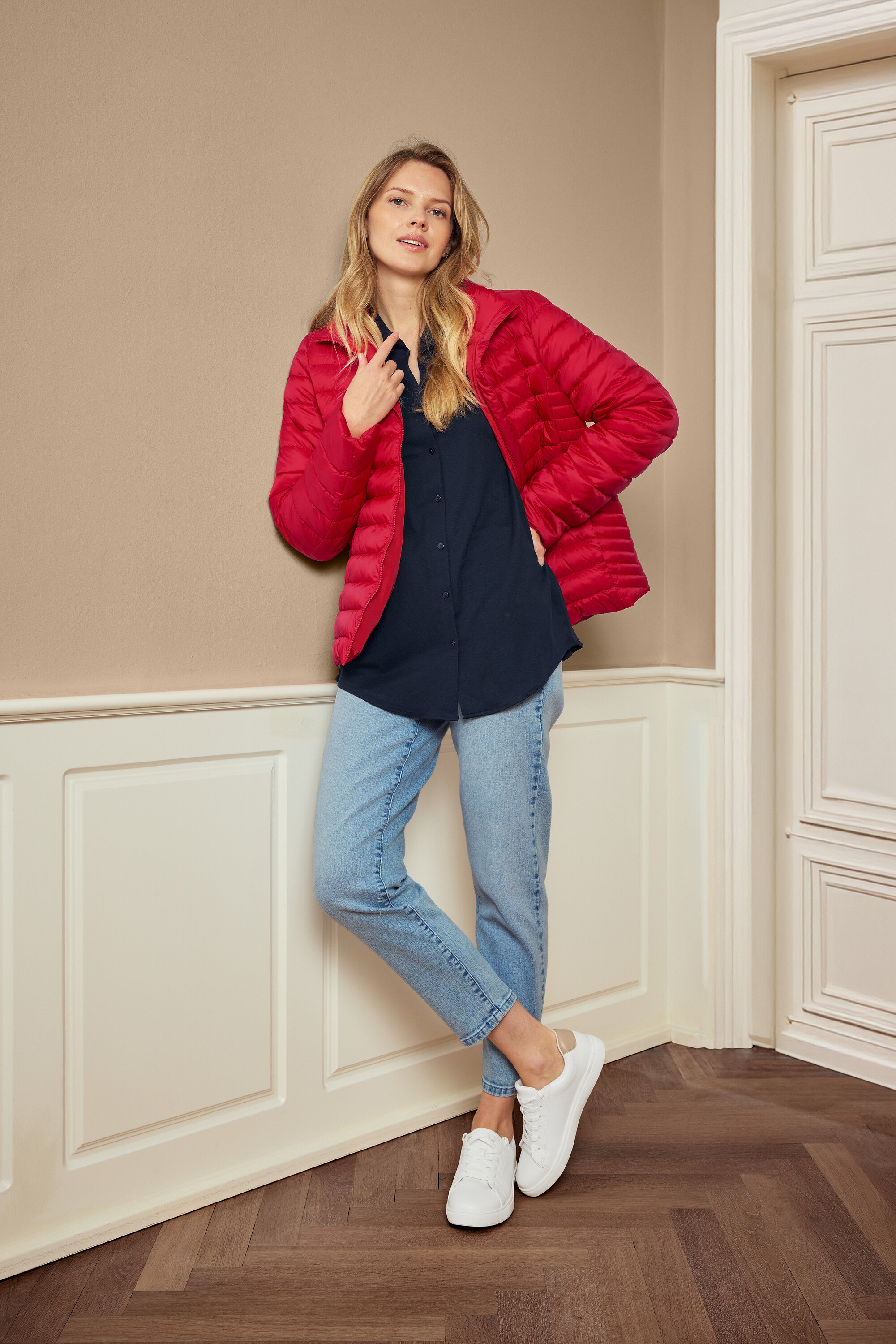 Frau posiert mit roter Jacke, blauem Hemd, Jeans und weißen Sneakern, trägt 925 Silber Creolen Hexagon.