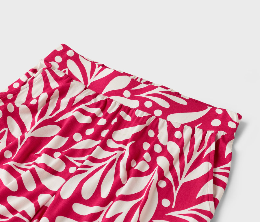 Detailansicht einer pinkfarbenen Hose mit weißem Blattmuster.
