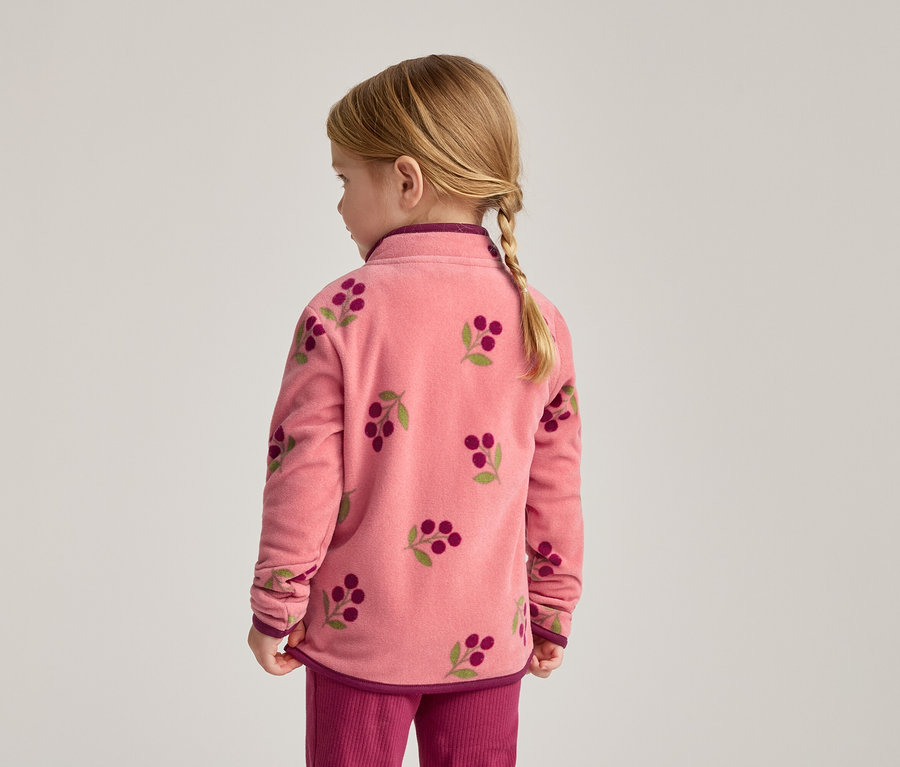 Von hinten ist ein Mädchen mit Zopf in einem rosa Fleece-Oberteil mit Kirschmuster und einer pinken Hose zu sehen.