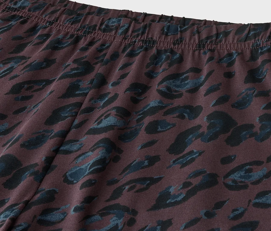 Nahaufnahme eines dunkelbraunen Stoffes mit dunkelblauem Animalprint-Muster, der einen elastischen Bund oben zeigt.