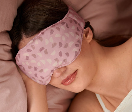 Frau schläft mit Gewichts-Schlafmaske im Bett.