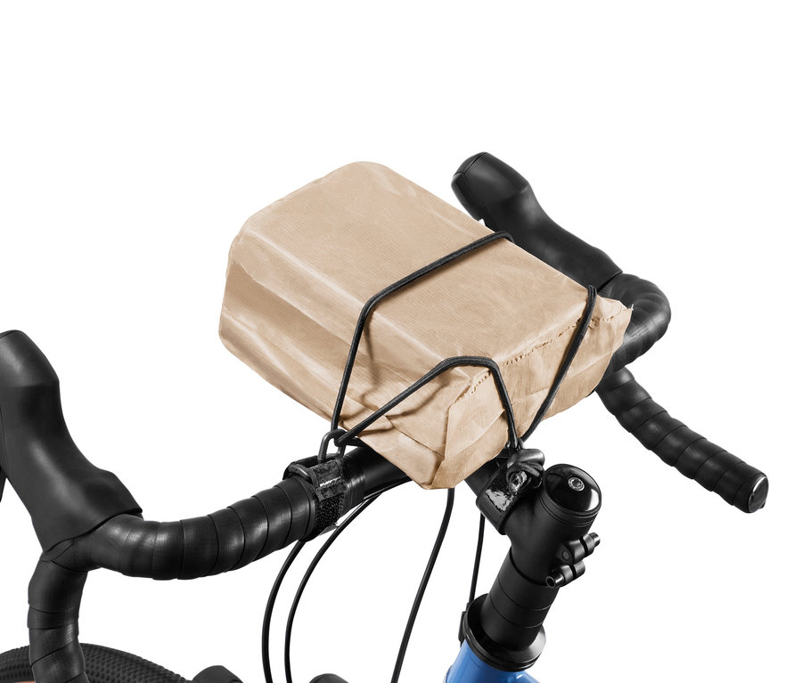 Braune Papiertüte mit Lenkerspannband am Fahrradlenker befestigt.