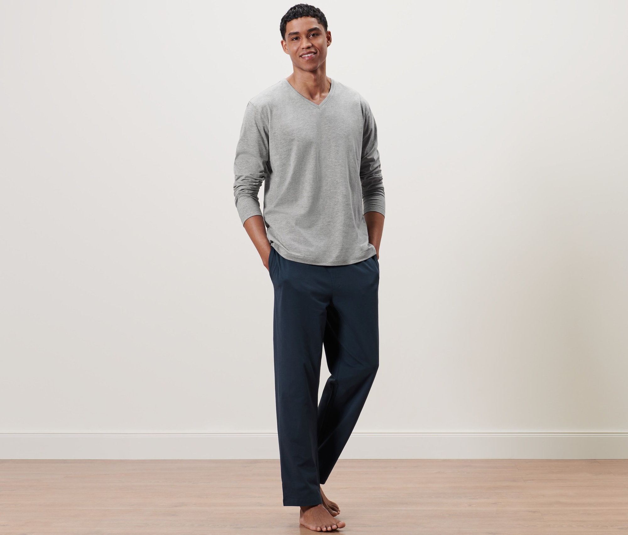 Mann steht mit Händen in den Taschen eines grau-blauen Pyjamas.