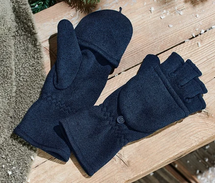 Zwei blaue Strickfleece-Klappfäustlinge liegen auf einer Holzbank. Daneben liegt eine braune Decke und Tannennadeln sind zu sehen.