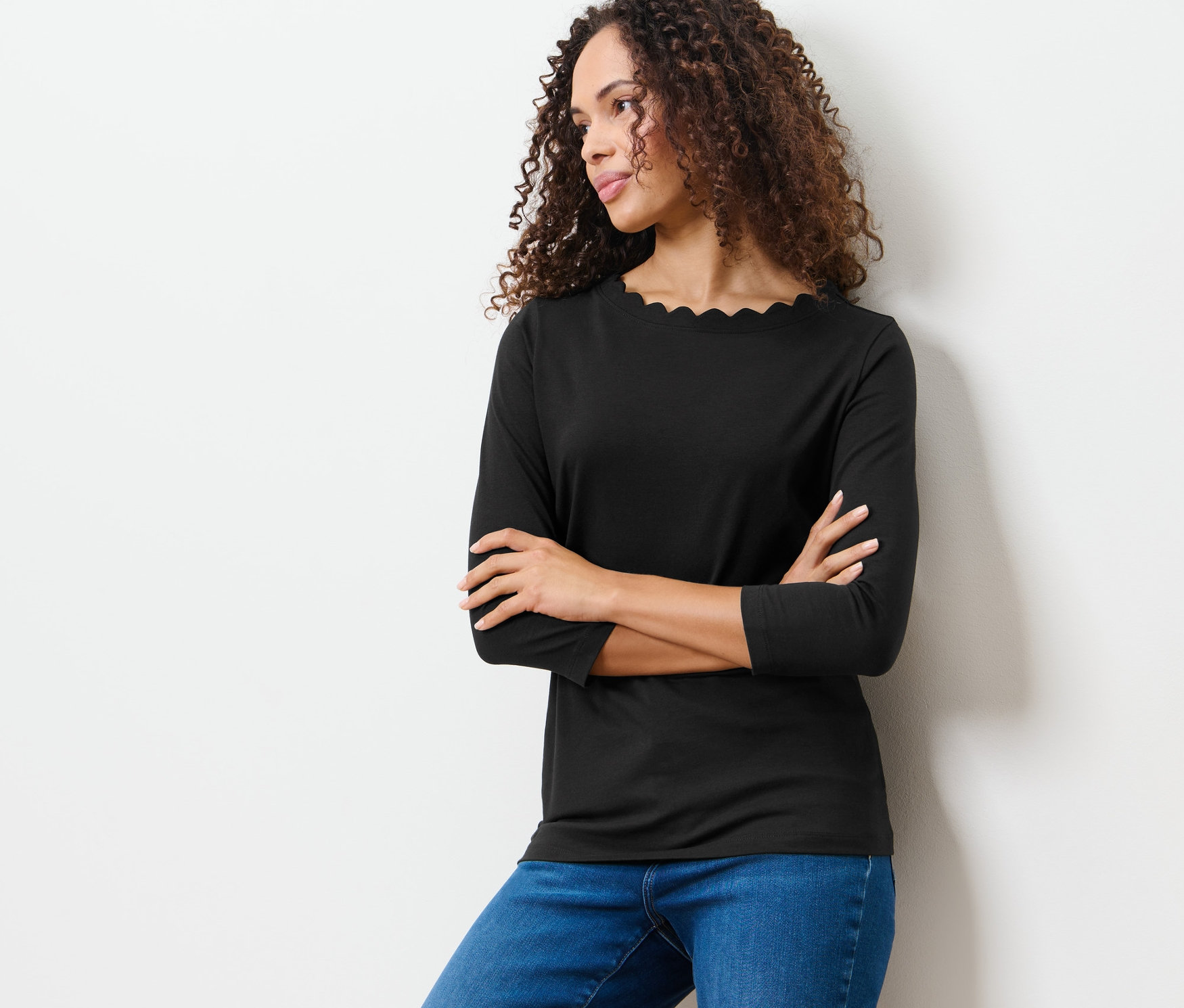 Frau posiert in einem schwarzen Shirt mit 3/4-Arm.