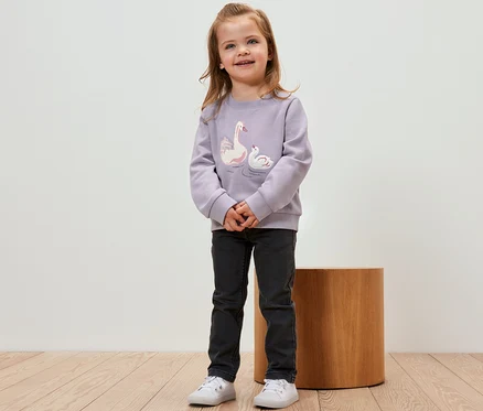 Mädchen trägt ein Kinder-Sweatshirt mit angerauter Innenseite und Schwan-Motiv.