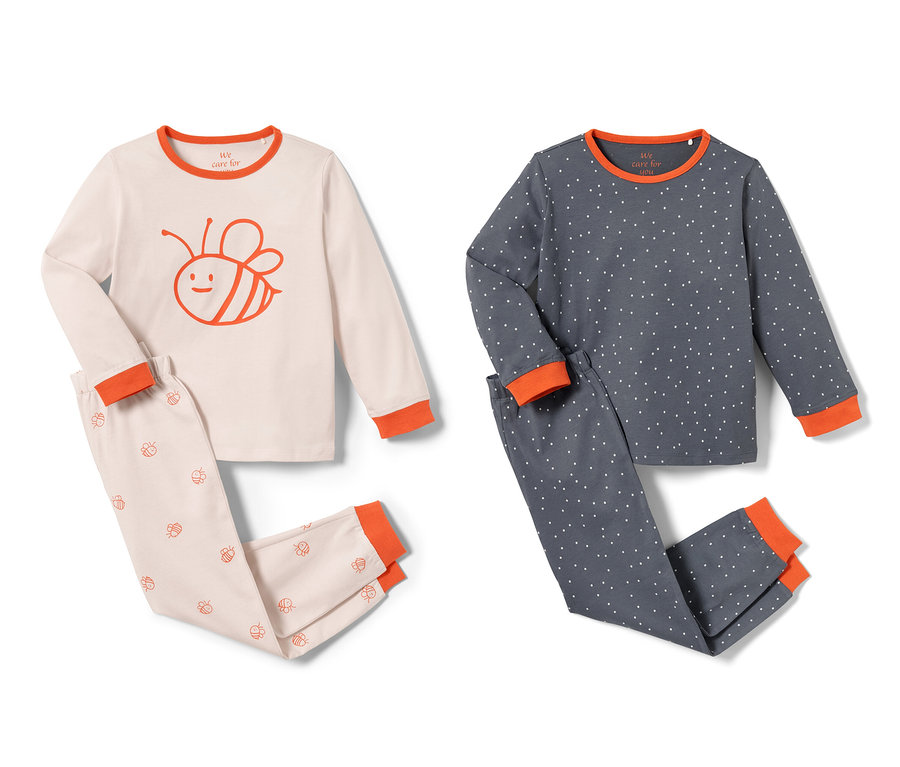 Zwei Kleinkinder-Pyjamas, einer rosa mit Bienenmuster, einer blau gepunktet.