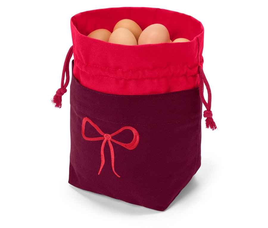 Stoffsack mit rotem Rand und weinrotem Boden, verziert mit einer roten Schleifenstickerei, gefüllt mit braunen Eiern.
