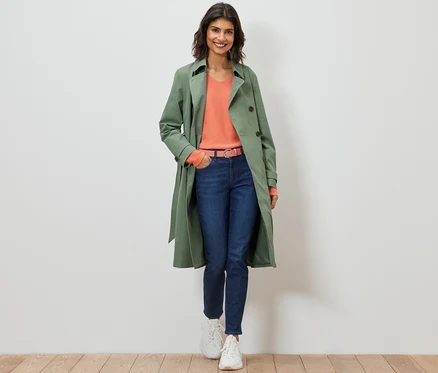 Frau geht und trägt einen hellgrünen Trenchcoat.