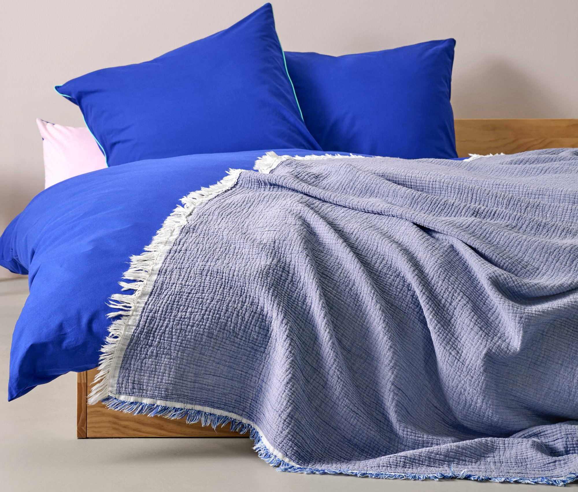 Auf einem Bett liegt ein blauer Bettüberwurf (220 x 240 cm).