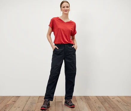 Frau steht mit Händen in den Taschen der schwarzen 2-in-1-Funktionshose.