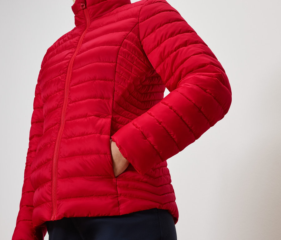 Person mit Hand in der Tasche einer roten Steppjacke.