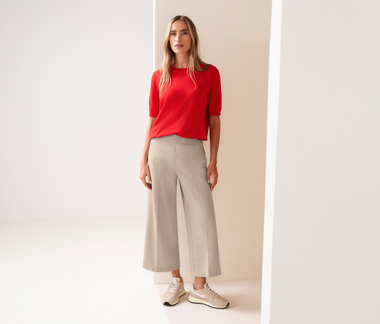 Frau mit rotem Oberteil und Street One 7/8-Culotte in Beige, dazu passende Turnschuhe.