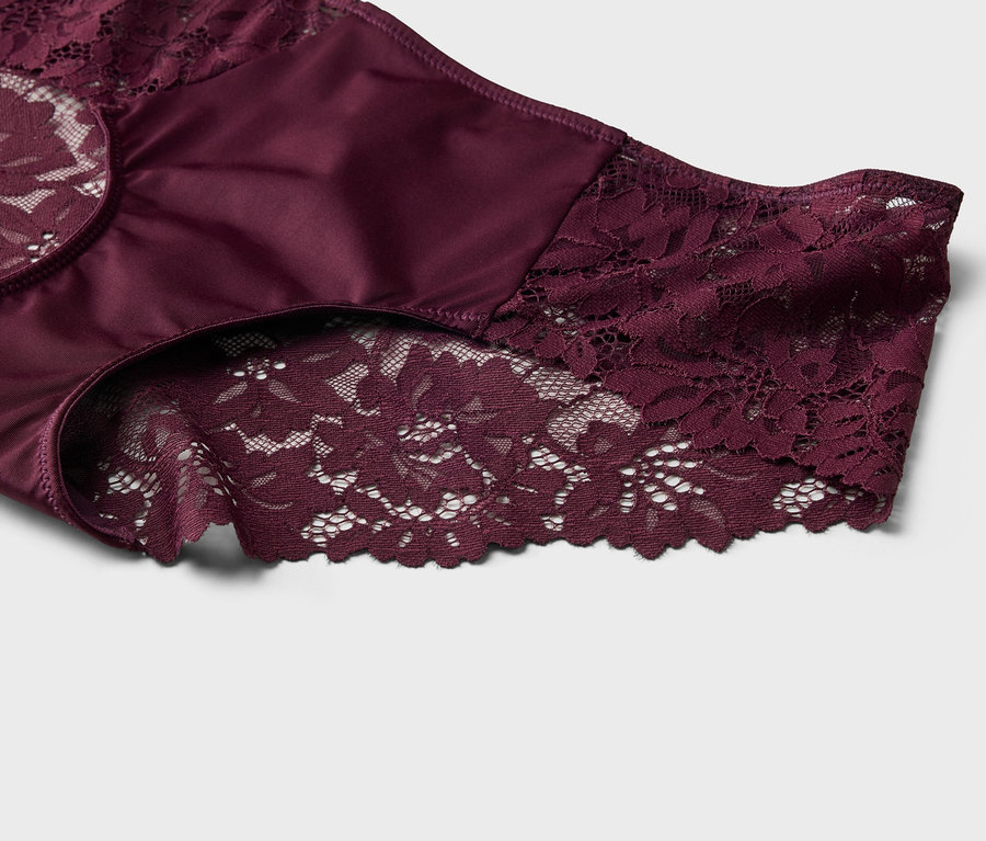 Nahaufnahme eines burgunderroten Damenslips mit Spitze und Satin auf einem weißen Hintergrund.