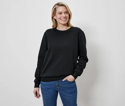 Frau mit blonden Haaren trägt einen schwarzen Pullover und Jeans.